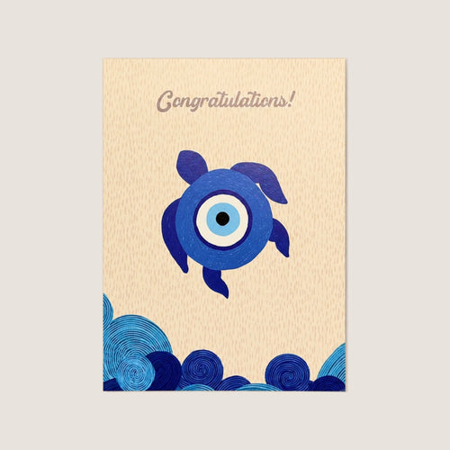 A vertical congratulations card with a textured beige background, featuring a blue and white evil eye turtle illustration in the center, stylized blue waves at the bottom, and the word 'Congratulations!' printed at the top.