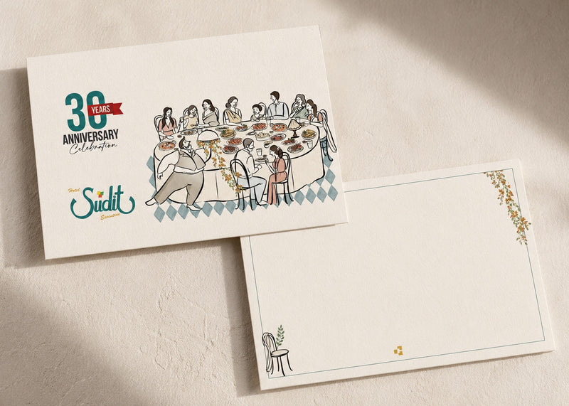 A printed anniversary card and matching envelope laid on a textured beige surface with soft diagonal shadows. The card features a vintage-style illustration of people dining around a table, with the text '30 Years Celebration' and the brand name 'The Sudit'.