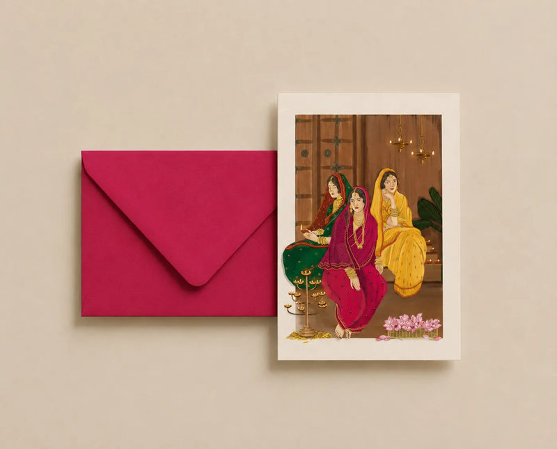 A vertical art print featuring an illustration of three women in traditional Indian attire, displayed next to a matching magenta envelope on a warm beige background.
